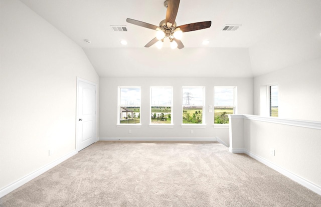 spare room with light carpet, vaulted ceiling, and visible vents
