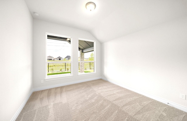 carpeted empty room with baseboards and lofted ceiling