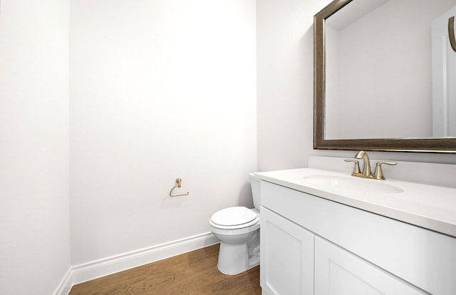 bathroom featuring toilet, baseboards, wood finished floors, and vanity