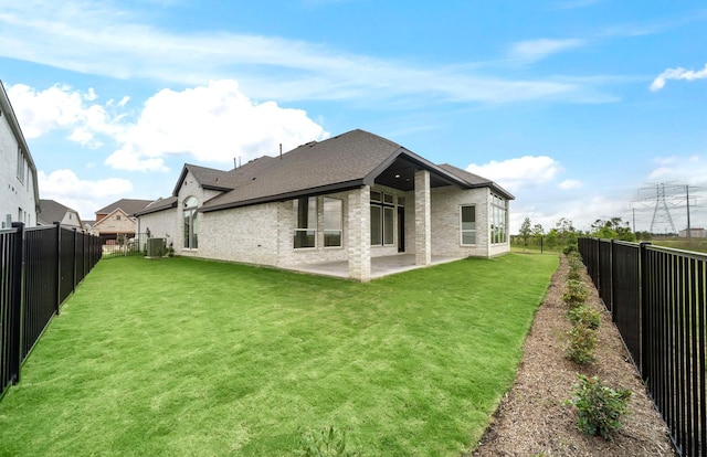 back of house with a yard, brick siding, a fenced backyard, and a patio area