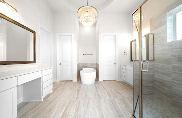 bathroom with an inviting chandelier, vanity, a stall shower, and a freestanding tub