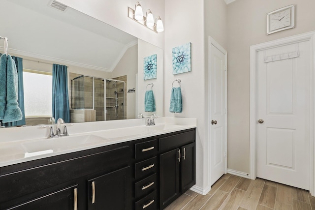 bathroom featuring crown molding, wood-type flooring, lofted ceiling, a shower with door, and vanity