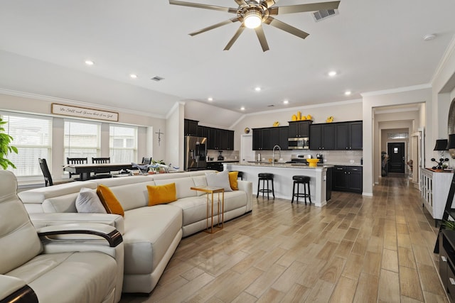 living room with ornamental molding, ceiling fan, sink, light hardwood / wood-style floors, and lofted ceiling