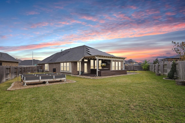 back house at dusk with a lawn and a patio area