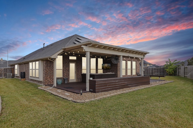 back house at dusk featuring a patio, central air condition unit, and a lawn