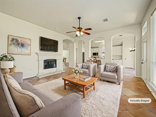 tiled living room with ceiling fan with notable chandelier