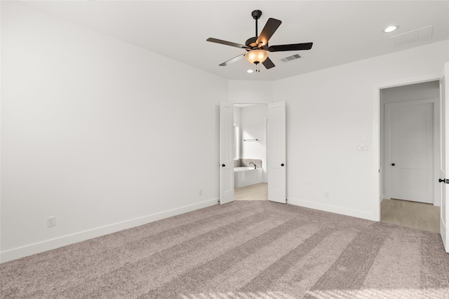 unfurnished bedroom featuring light carpet, ensuite bathroom, and ceiling fan