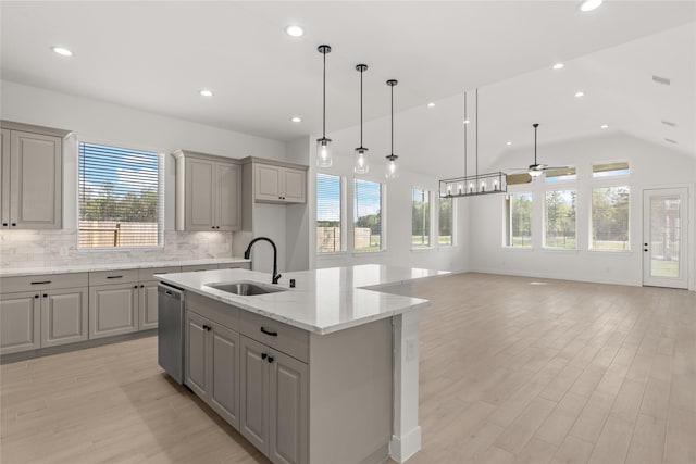 kitchen with gray cabinetry, a sink, open floor plan, stainless steel dishwasher, and a center island with sink