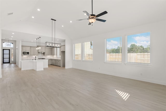 unfurnished living room featuring light wood finished floors, visible vents, baseboards, and a ceiling fan