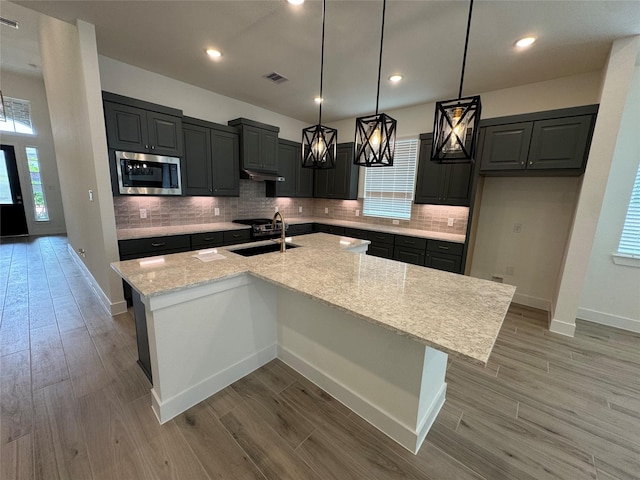 18101 Brennie Bird Ln, Conroe, TX 77302 - kitchen featuring stainless steel microwave, a sink, light wood-style floors, and recessed lighting