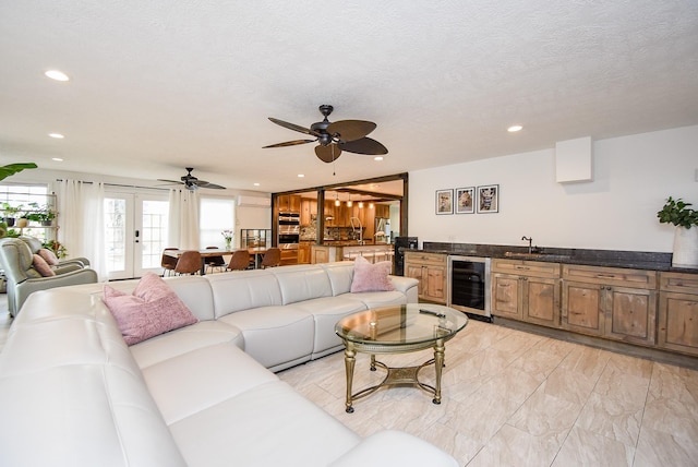 living room with french doors, a textured ceiling, wine cooler, and ceiling fan