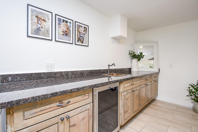 kitchen with light brown cabinetry, sink, beverage cooler, and light hardwood / wood-style flooring