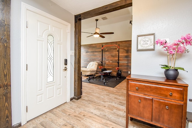 entryway with wood walls, ceiling fan, and light hardwood / wood-style floors