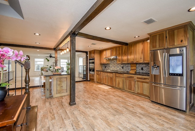 kitchen featuring beam ceiling, ceiling fan, stainless steel appliances, light hardwood / wood-style floors, and a breakfast bar