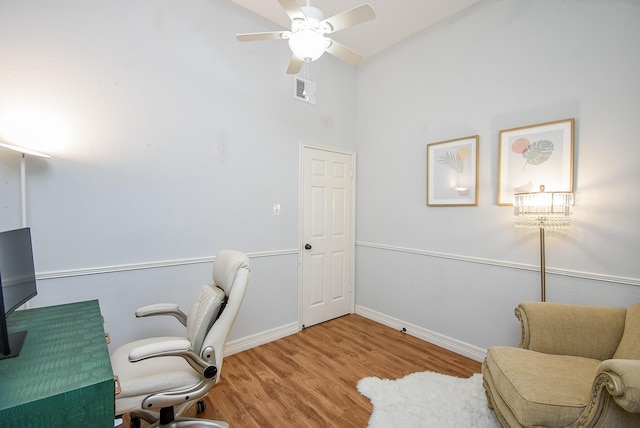 office space with ceiling fan, a towering ceiling, and light wood-type flooring