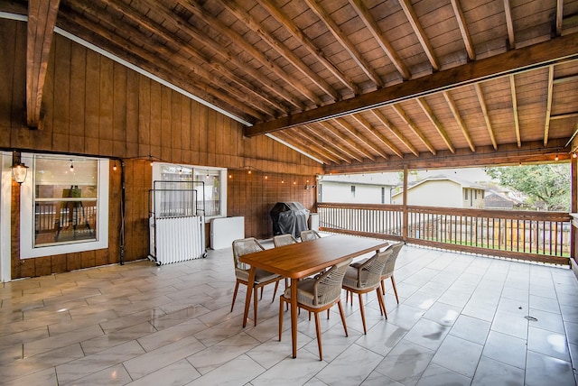 dining area with beamed ceiling, high vaulted ceiling, wood ceiling, and wooden walls