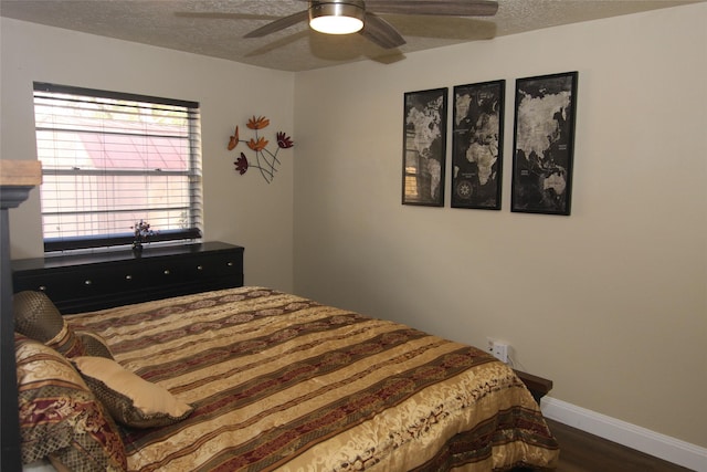 bedroom with a textured ceiling, ceiling fan, and dark wood-type flooring