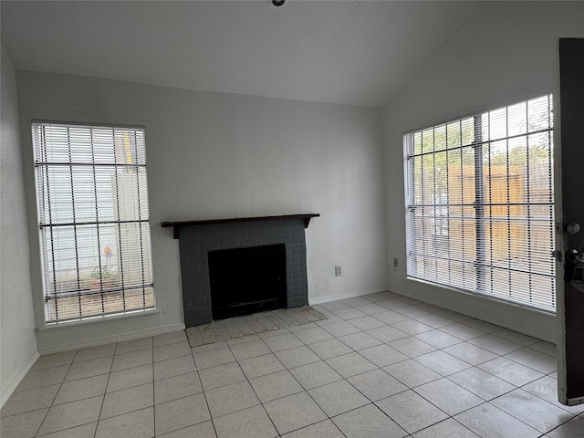 unfurnished living room with a fireplace, light tile patterned floors, and lofted ceiling