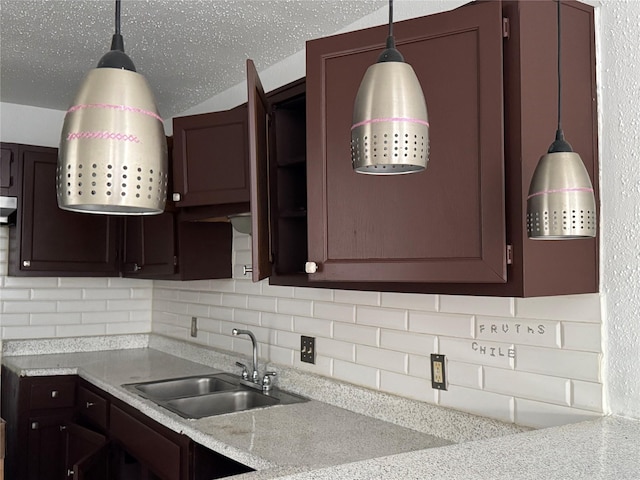 kitchen featuring decorative backsplash, sink, pendant lighting, and light stone counters