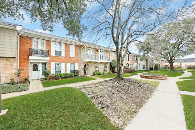 view of property with a balcony and a front lawn