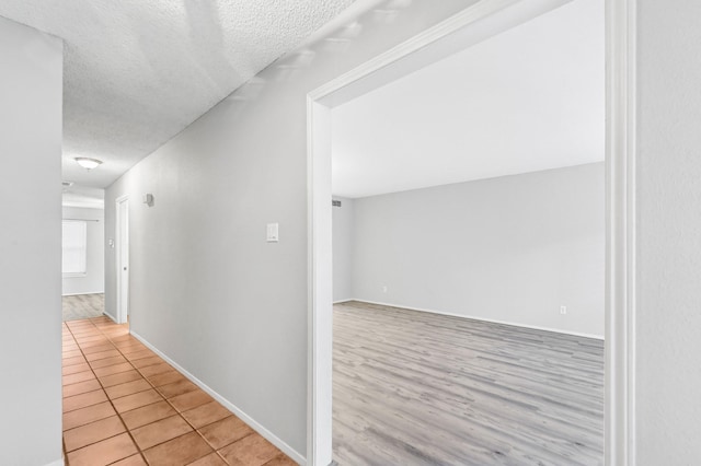 corridor with a textured ceiling and light wood-type flooring