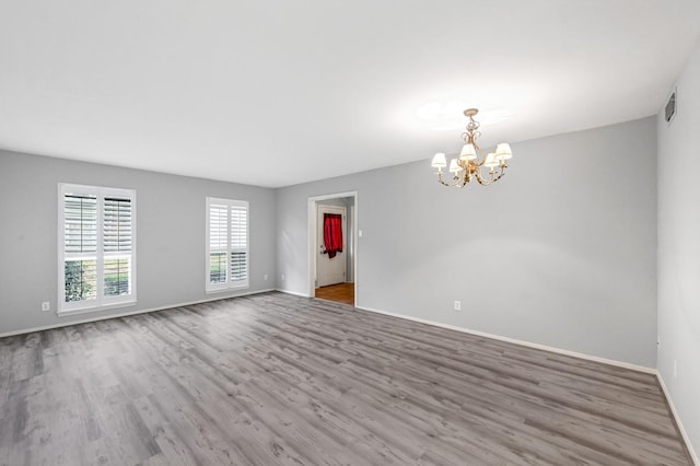 spare room with light wood-type flooring and an inviting chandelier