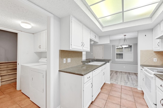 kitchen featuring washing machine and clothes dryer, white cabinetry, sink, tasteful backsplash, and white appliances