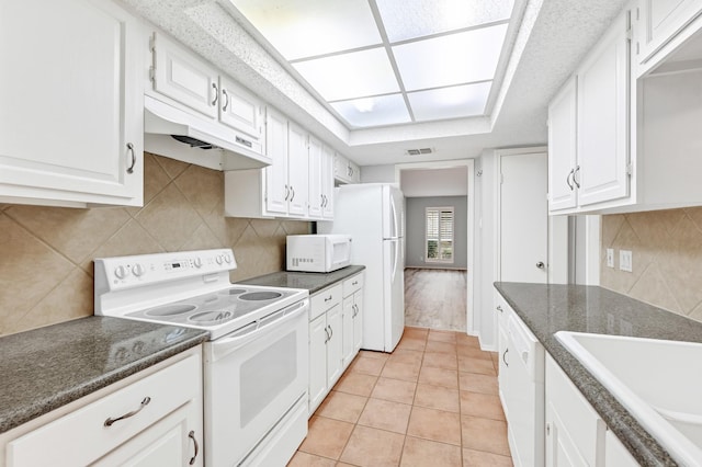 kitchen with decorative backsplash, light tile patterned floors, white appliances, and white cabinetry