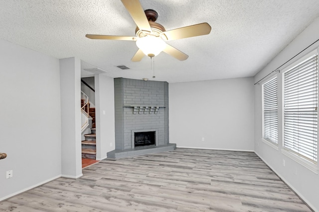 unfurnished living room with ceiling fan, plenty of natural light, light wood-type flooring, and a textured ceiling