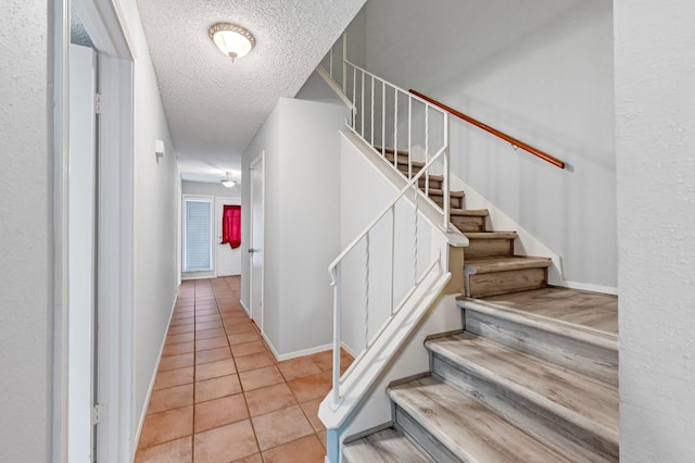 stairs with tile patterned floors and a textured ceiling