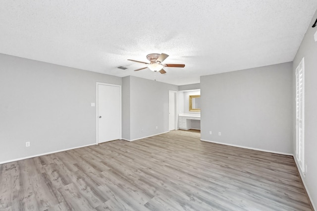 empty room featuring ceiling fan, light wood-type flooring, and a textured ceiling