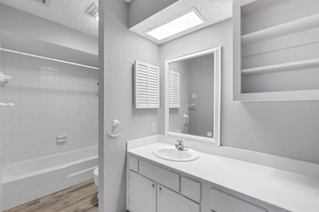 full bathroom featuring a skylight, toilet, hardwood / wood-style flooring, vanity, and tiled shower / bath