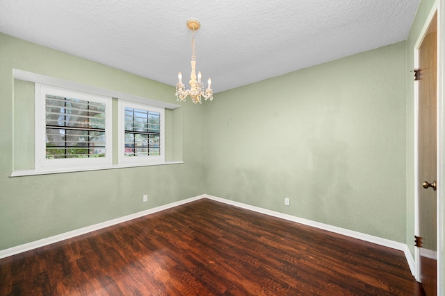 empty room with a chandelier, wood-type flooring, and a textured ceiling