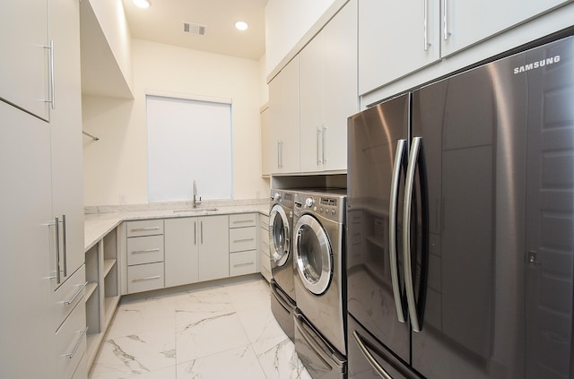 laundry area with washing machine and dryer, sink, and cabinets