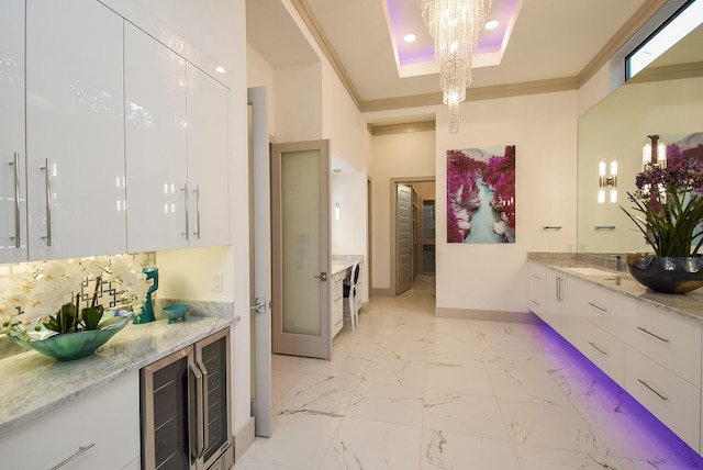 bathroom featuring ornamental molding, vanity, a tray ceiling, beverage cooler, and a notable chandelier