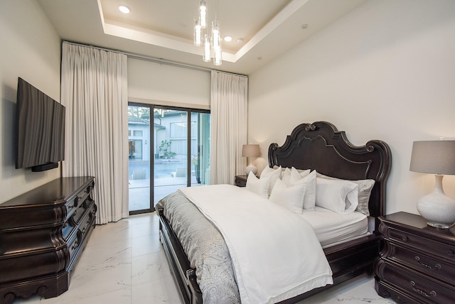 bedroom with access to exterior, a raised ceiling, and an inviting chandelier