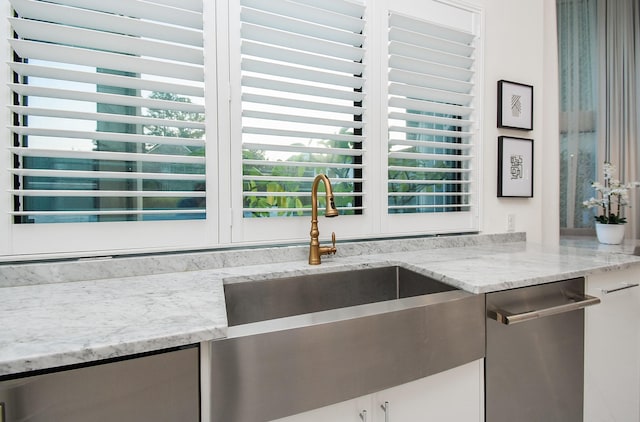 kitchen featuring light stone counters, plenty of natural light, and sink