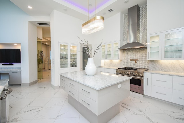 kitchen featuring wall chimney exhaust hood, a center island, white cabinetry, and stainless steel appliances