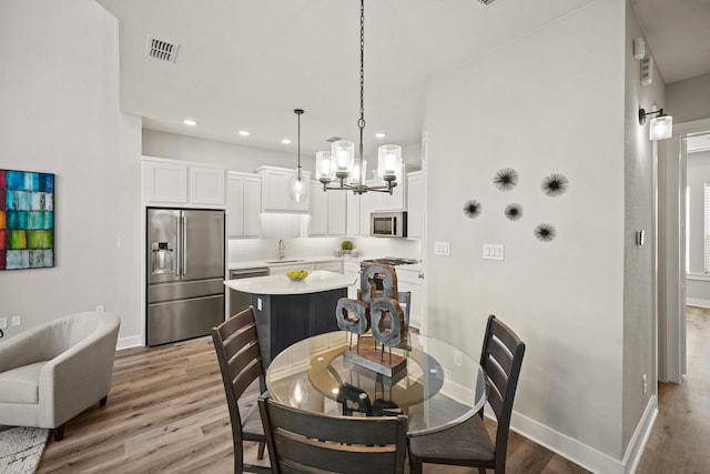 dining space with a notable chandelier, light wood-type flooring, and sink