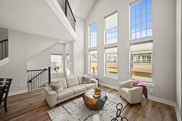 living room featuring a towering ceiling and dark wood-type flooring