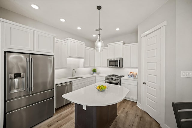 kitchen with decorative light fixtures, a center island, high quality appliances, and light hardwood / wood-style floors