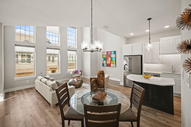 dining space featuring a chandelier, sink, and light hardwood / wood-style flooring