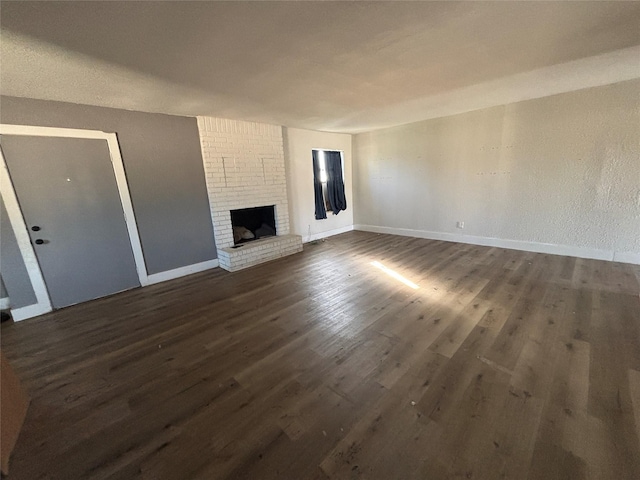 unfurnished living room with dark hardwood / wood-style flooring and a brick fireplace