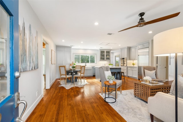 living room with light wood-type flooring and ceiling fan