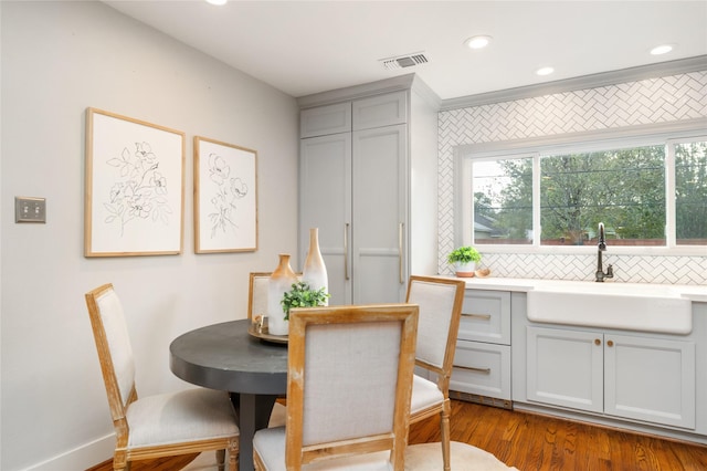 dining room featuring light hardwood / wood-style floors, crown molding, and sink