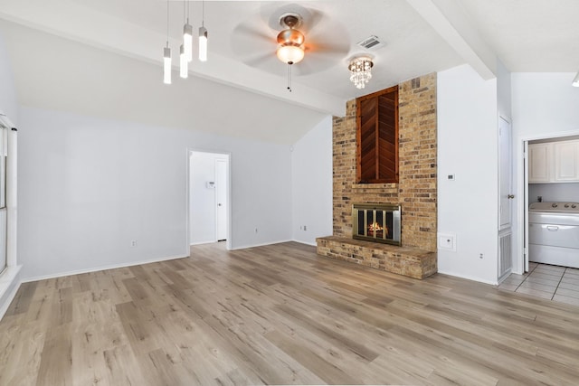 unfurnished living room featuring light wood-type flooring, ceiling fan, lofted ceiling with beams, a fireplace, and washer / dryer