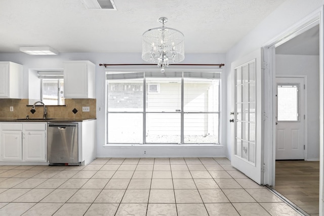 kitchen featuring stainless steel dishwasher, pendant lighting, white cabinetry, and an inviting chandelier