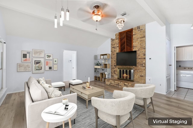 living room featuring ceiling fan, a brick fireplace, vaulted ceiling with beams, light hardwood / wood-style flooring, and washer / clothes dryer