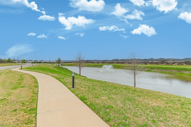 view of property's community with a lawn and a water view