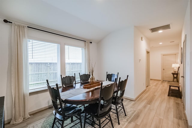 dining area featuring vaulted ceiling and light wood-type flooring